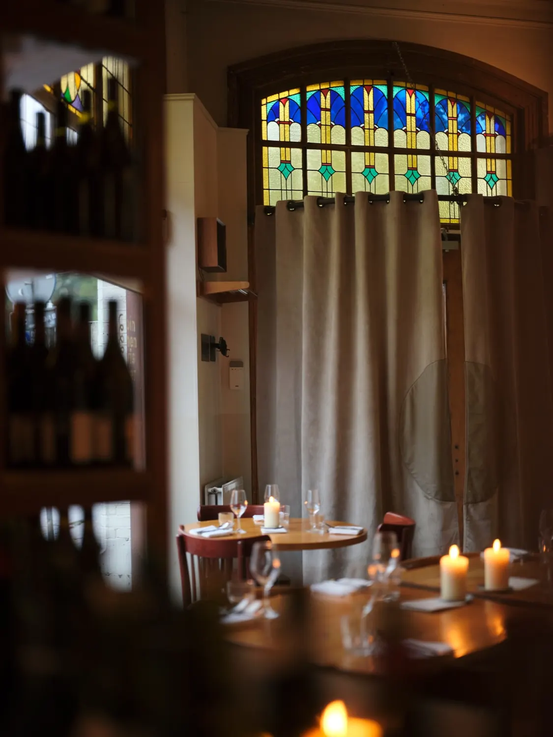 candlelit tables under a stained-glass arch